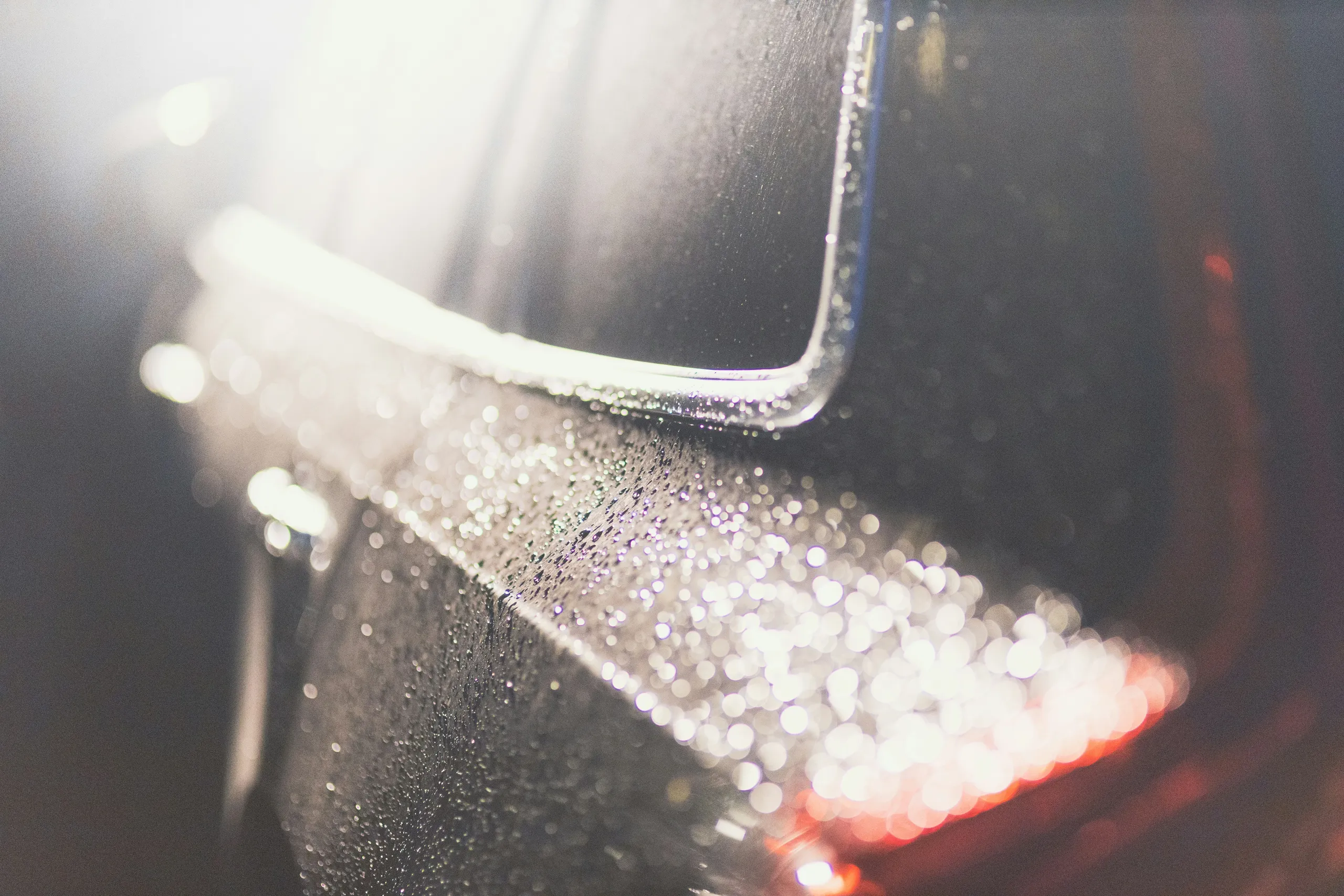 Primer plano de la pintura de un coche con gotas de agua en el estudio de detailing